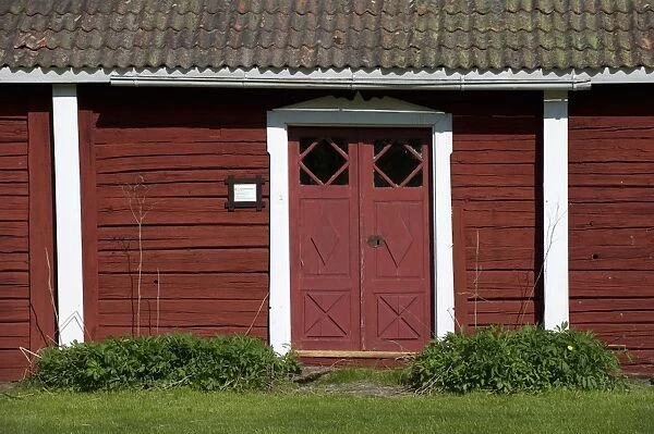 Red door and wooden walls of old house, Hellstromsgarden, Hallnas, Vasterbotten County, Uppland, Sweden, may