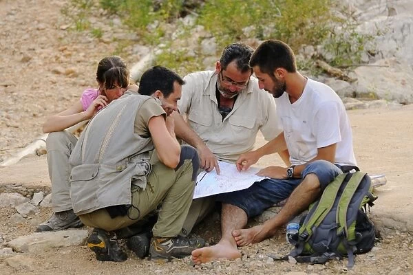 Researchers looking at map in desert, Socotra, Yemen, march
