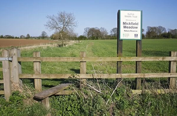 Reserve sign, stile and path beside arable fields towards unimproved hay meadow reserve