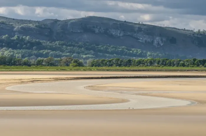 Framed Print : River meandering through sands of estuary at low tide, looking from Sandside, River Kent, Kent Estuary, Cumbria