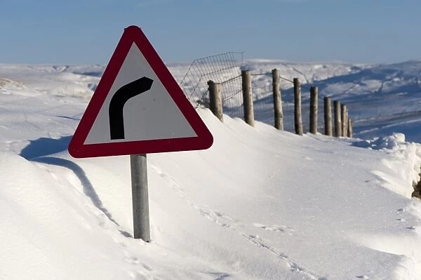 Road sign in snowdrift at roadside, Upper Swaledale, North Yorkshire, England, december