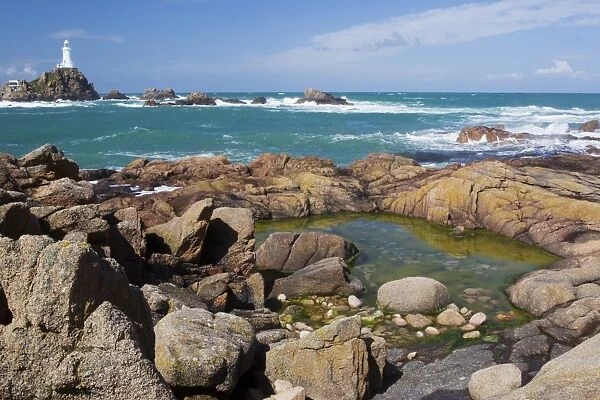 Rockpool on rocky shore at low tide, with lighthouse in background, La Corbiere Lighthouse, La Corbiere, St