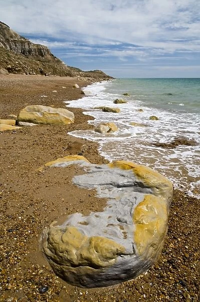 Rocks on beach and in sea under sandstone cliffs, Fairlight Cove, Covehurst Bay, near Hastings, East Sussex, England