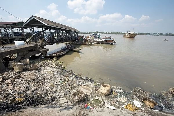 Rubbish at edge of river with jetty and boats, Yangon, Myanmar, March