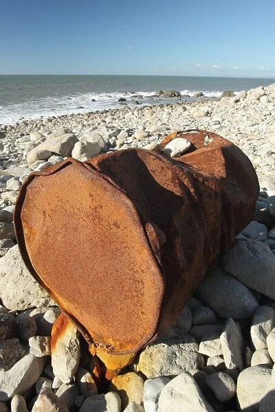 Rusty metal oil drum washed up on beach, Portland, Dorset, England, November