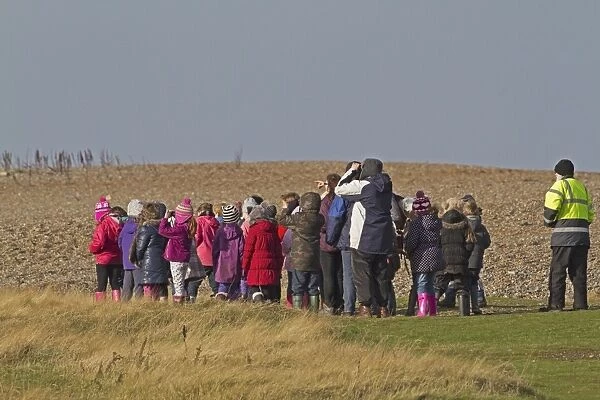 School group birdwatching on coast, Norfolk, England, November