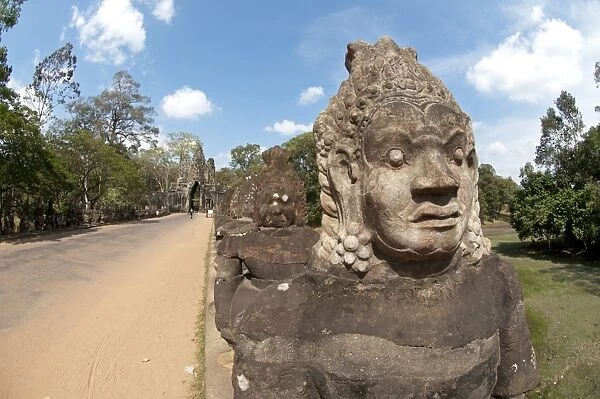 Sculptures of Asuras (demonic monsters) lining road to gate tower of Khmer temple, South Gate, Angkor Thom, Siem Riep