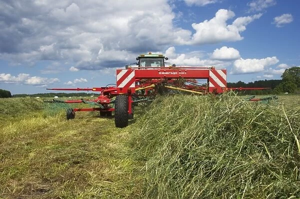 Silage crop, tractor with double turner, turning cut grass for silage, Sweden, august