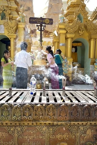 Smoke from incense burning with people at Buddhist alter, Shwedagon Pagoda, Yangon, Myanmar, March