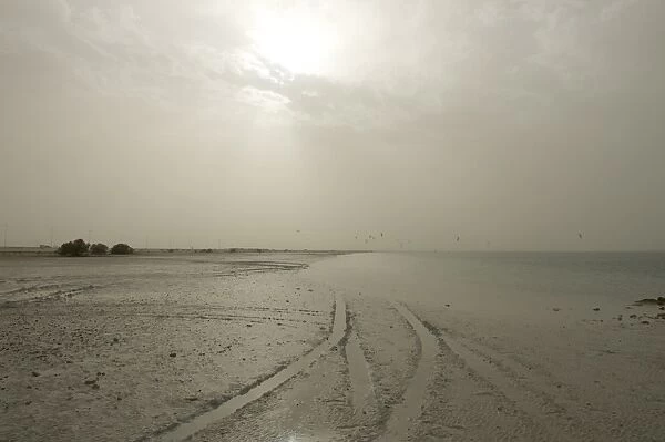 Sudden sandstorm developing over beach blotting out sun and catching distant kite surfers, Arabian Gulf, Abu Dhabi
