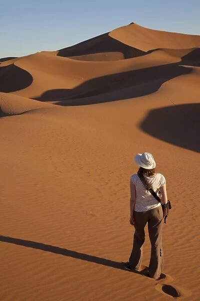 Tourist standing on desert sand dunes, Erg Chegaga, Sahara, Morocco, may