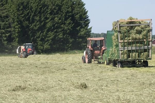 Tractor baling hay crop, pulling baler and wagon, Sweden