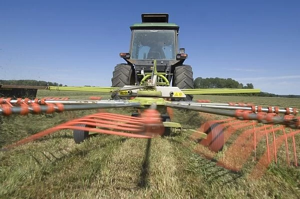 Tractor with Cls Liner 350 rotary rake, turning cut grass for silage crop, Sweden