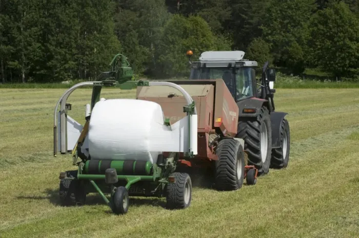 Framed Print : Tractor pulling baler and mechanical bale-wrapper, with plastic wrapped round silage bale, Sweden