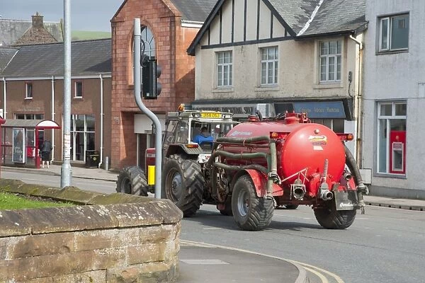 Tractor with slurry tanker, travelling through town, Lockerbie, Dumfries and Galloway, Scotland, march
