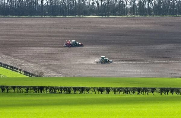 Tractors cultivating and drilling cereal crop in arable farmland, Tibthorpe, North Yorkshire, England, march