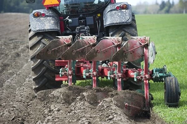 Valtra tractor ploughing field with four furrow reversible plough, Sweden, may