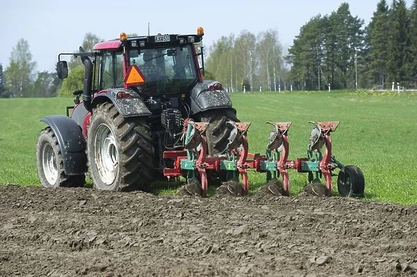 Valtra tractor ploughing field with four furrow reversible plough, Sweden, may