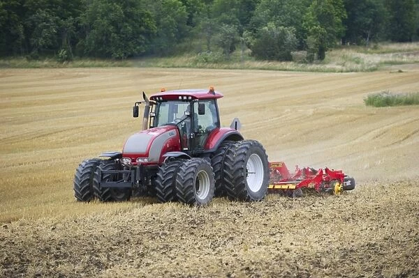 Valtra tractor pulling Vaderstad Carrier 420 cultivator, cultivating stubble field, Sweden, august