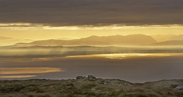 View across bay towards distant hills at sunrise, looking towards Lake District (Cumbria, England), Solway Firth