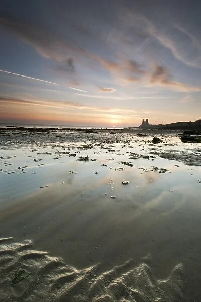 View of beach at low tide, with 12th Century ruined church in distance, at sunrise, St