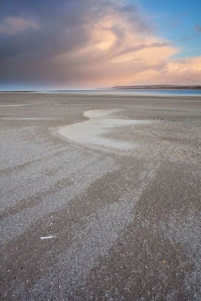 View of beach with rainclouds at sunrise, looking towards Baggy Point, Taw and Torridge Estuaries, North Devon