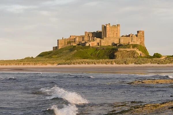 View across beach and sea towards castle, Bamburgh Castle, Northumberland, England, may