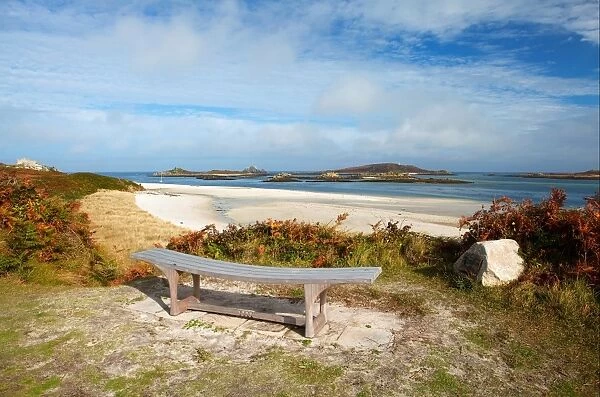 View of bench, sandy beach and coastline, looking towards Foremans Island, Northwethel and Round Island on horizon