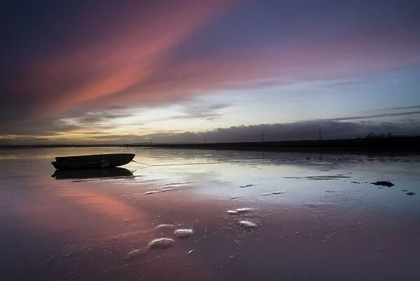 View of clouds and boat reflected in mud at sunrise, Oare Creek, Oare, Faversham, North Kent, England, January