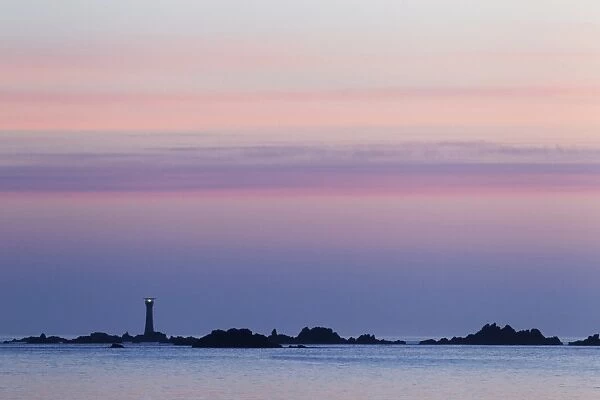 View of coastline with lighthouse at sunset, L Eree Bay, Guernsey, Channel Islands, May