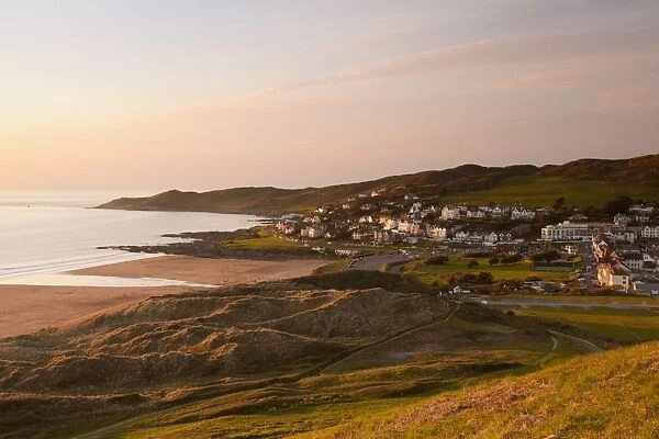 View of coastline and seaside resort at sunset, with Morte Point in distance, viewed from Potters Hill, Woolacombe
