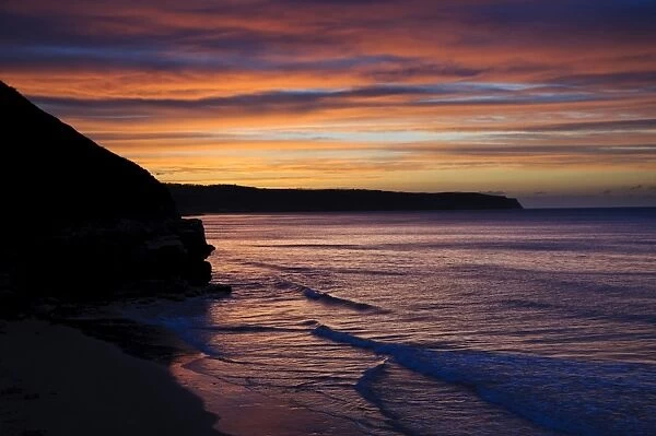 View of coastline silhouetted at sunset, looking from West Pier, Whitby, North Yorkshire, England, April