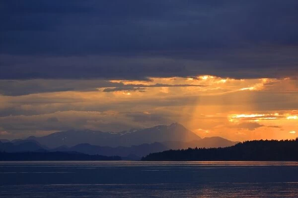 View of coastline and temperate coastal rainforest with sunbeams at sunrise, Queen Charlotte Strait, Inside Passage