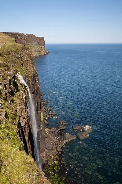 View of coastline with waterfall tumbling over cliffs into sea, with Kilt Rock in background, Mealt Falls
