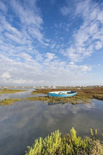 View of estuary saltmarsh habitat and boats with rising tide, Brancaster Staithe, Norfolk, England, September