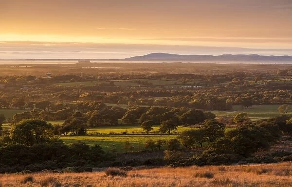 View of farmland on coastal plain at sunset, looking towards Morecambe Bay with Lake District fells in background
