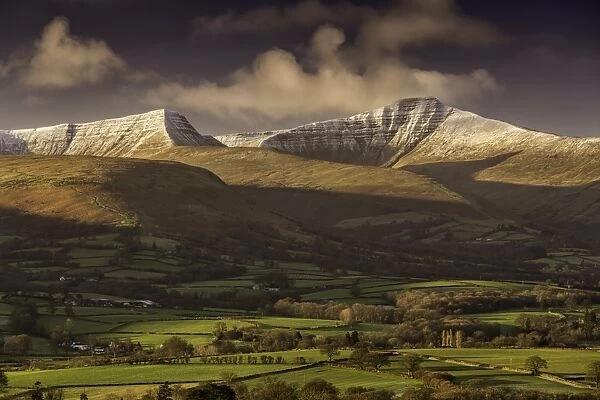 View of farmland and snow covered hills at sunrise, Penyfan and Corn Du, Brecon Beacons N. P