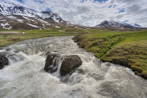 View of fast flowing river with mountains in background, Iceland, June