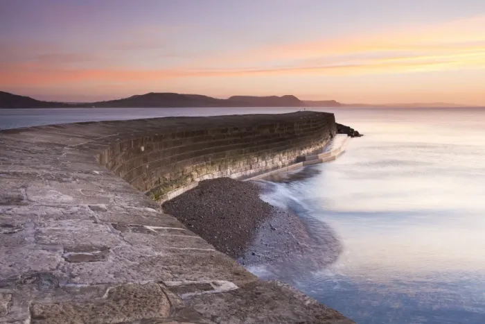 Framed Print : View of harbour wall at low tide during sunrise, looking across bay to Charmouth, Stonebarrow, Golden Cap and beyond Framed Print : View of harbour wall at low tide during sunrise, looking across bay to Charmouth, Stonebarrow, Golden Cap and beyond