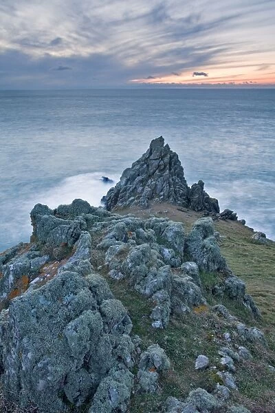 View of jagged basaltic rocks on coastal headland at sunset, Rumps Point, Pentire Head, Cornwall, England, March