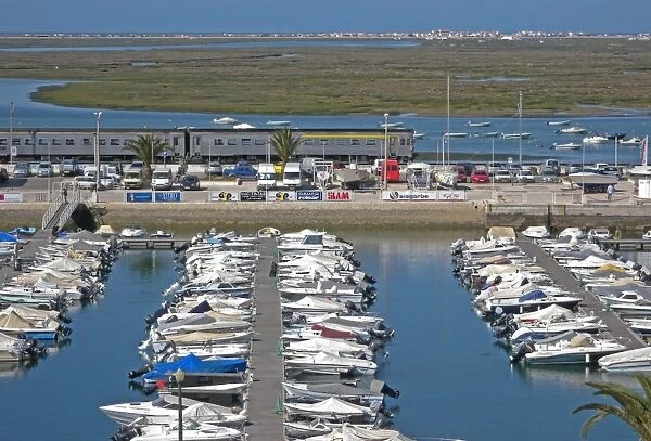 View over marina with passing train, with estuary and saltmarsh habitat in background, Faro, Algarve, Portugal, april