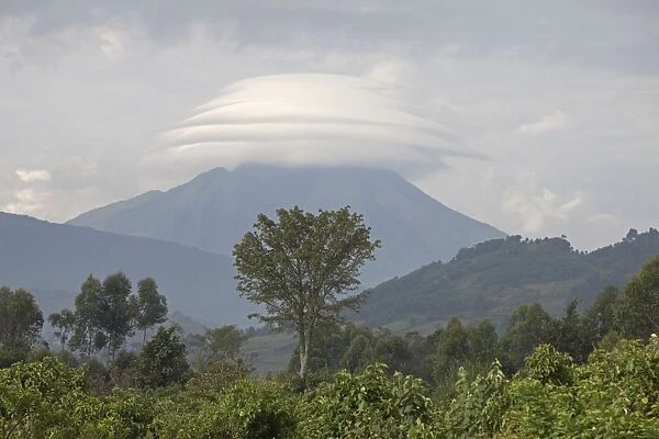 View of montane landscape and distant volcano with lenticular cloud formation, Virunga Mountains, Uganda
