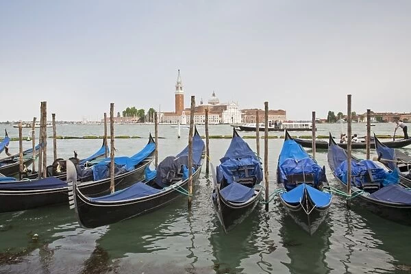 View of moored gondolas across waterway towards 16th century Benedictine church, Church of San Giorgio Maggiore