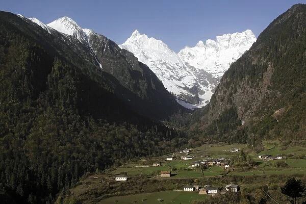 View of mountain valley with village at dawn, with snow covered peaks in background, Lower Yubeng Village, Miancimu