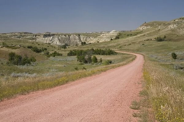 View of red scoria road in ranch country, Badlands, North Dakota, U. S. A. august