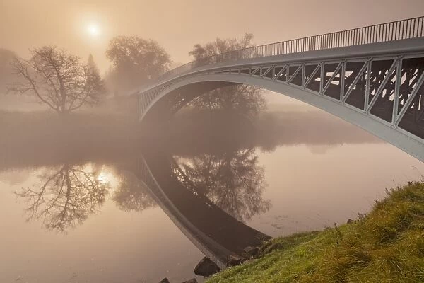 View of river and cast iron road bridge in mist at dawn, Bigsweir, River Wye, Wye Valley, on border of Gloucestershire