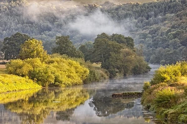 View of river with early morning mist clearing at dawn, Bigsweir, River Wye, Wye Valley, on border of Gloucestershire