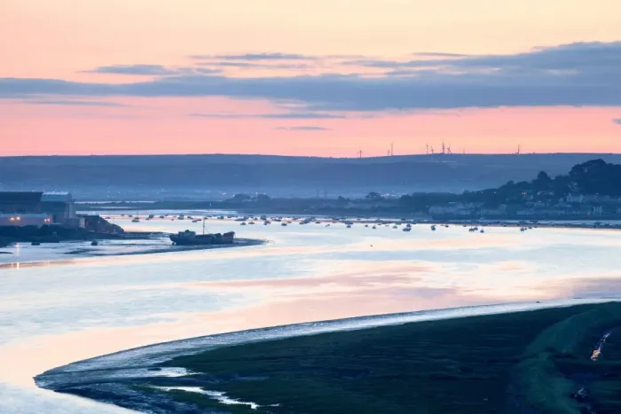 Framed Print : View of river estuary with shipyard, village and distant windfarm on banks at sunrise, Fullabrook Windfarm