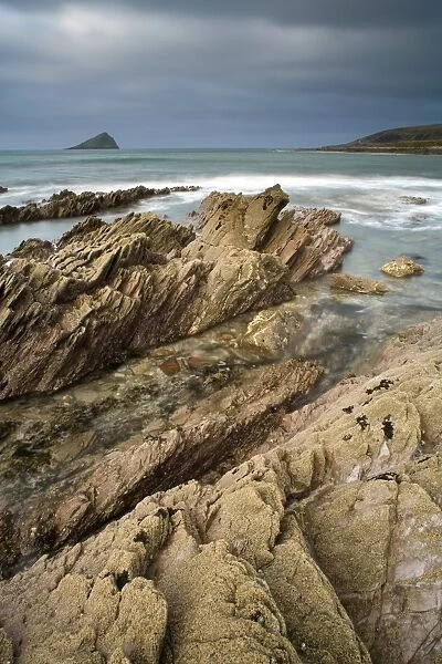 View of rocky beach, with Wembury Point and Great Mewstone Island in distance, Wembury Bay, Devon, England, march