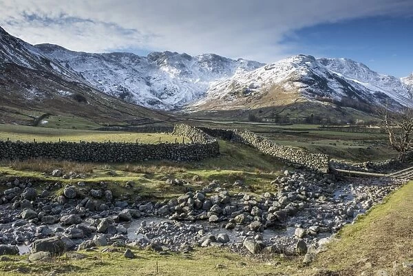 View across rocky stream, drystone walls and valley pasture towards snow covered fell, Langdale Fell, Great Langdale